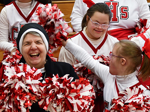 Sister smiling and taking a picture with CH pompom team